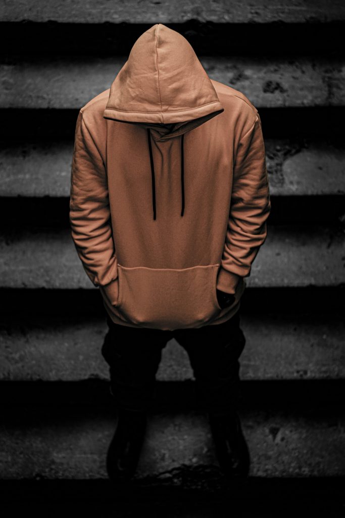 Person in a hooded sweatshirt standing on dark concrete steps