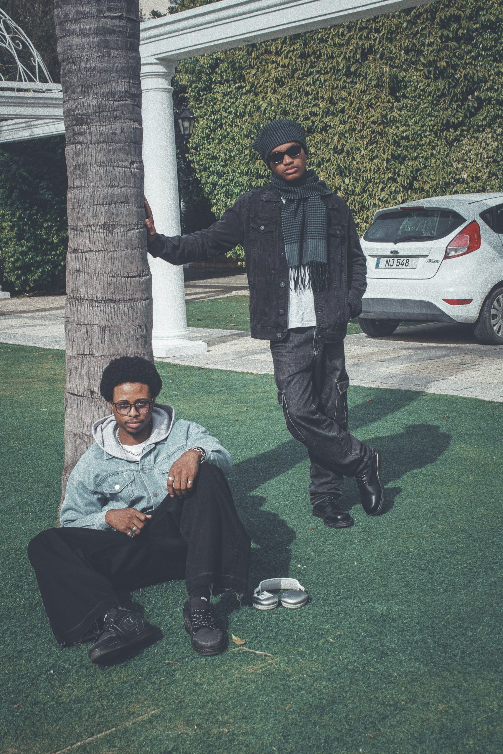 Two friends in relaxed streetwear hanging out on a lawn
