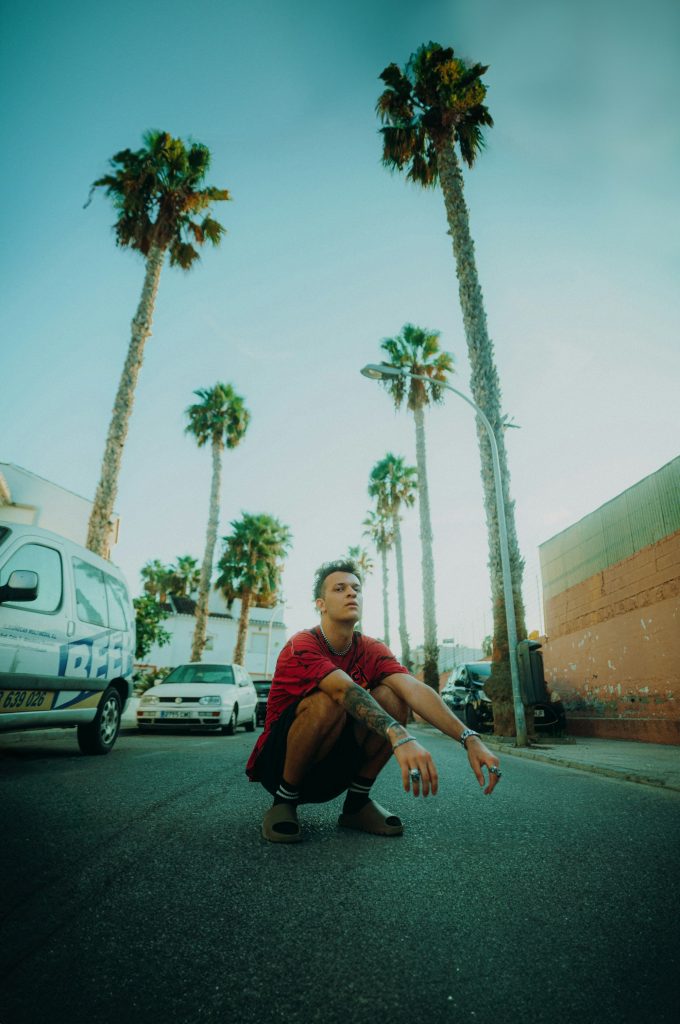 Man crouching on a palm-lined street
